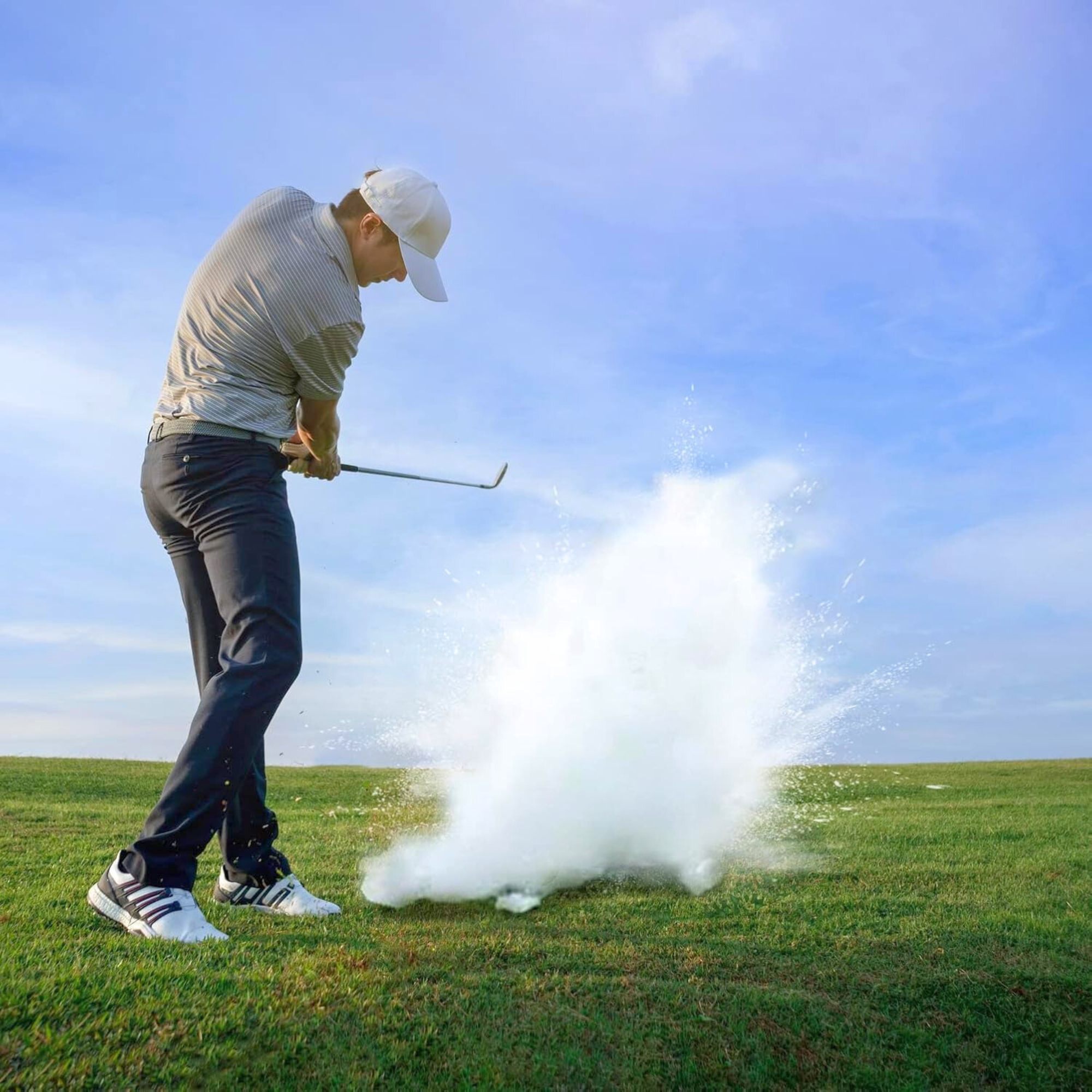 Golfer hitting a prank golf ball with a large white cloud of smoke explosion on a clear day golf course.