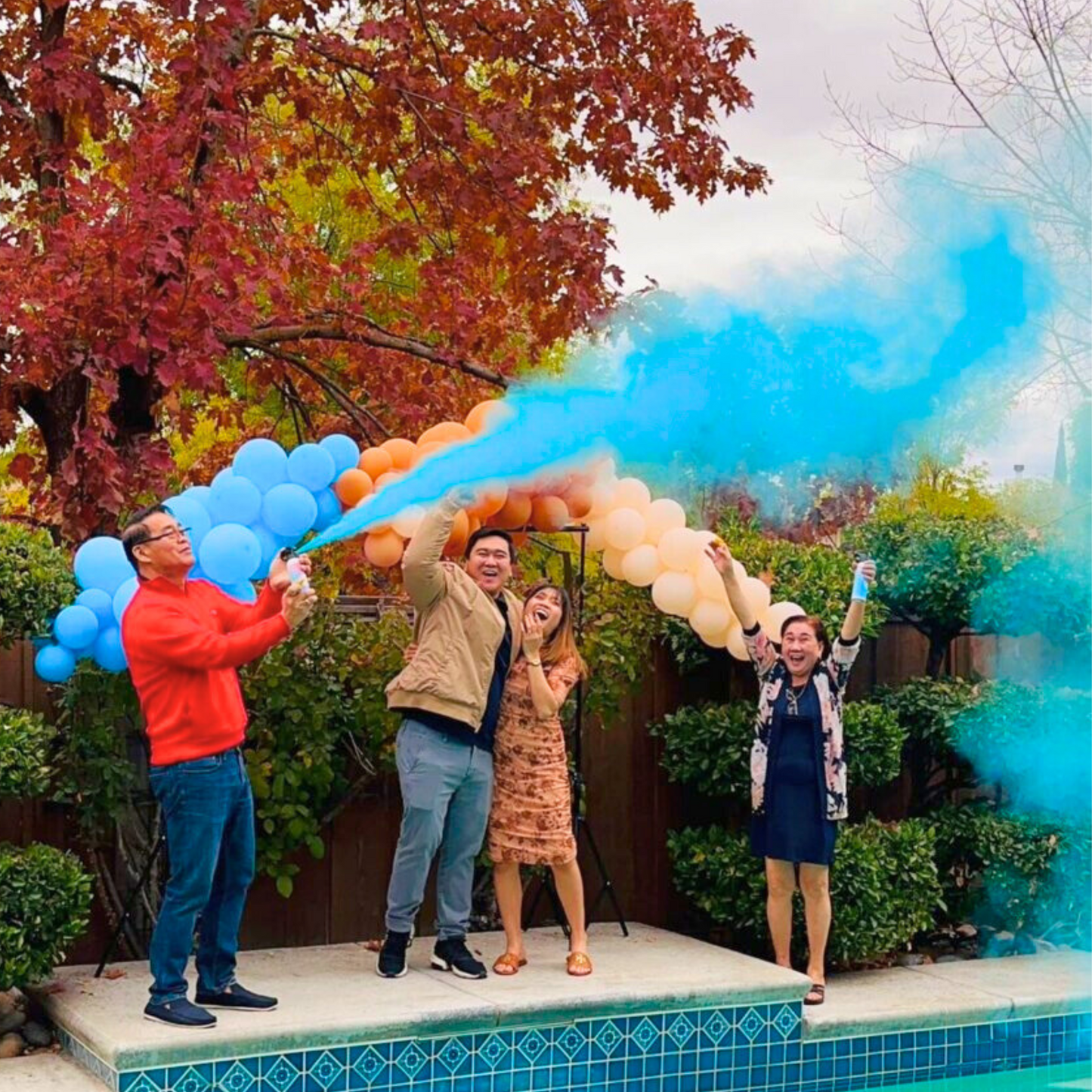Group celebrating with blue gender reveal baby blaster at outdoor gender reveal celebration.