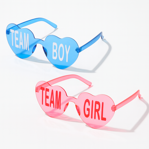 Heart-shaped Team Boy and Team Girl glasses in blue and pink for gender reveal or baby shower party celebrations, shown on a white background.